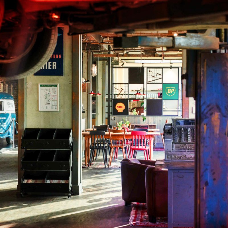 Retro-Café mit Oldtimer, bunten Stühlen und alten Tankstellen-Schildern im Industriestil
